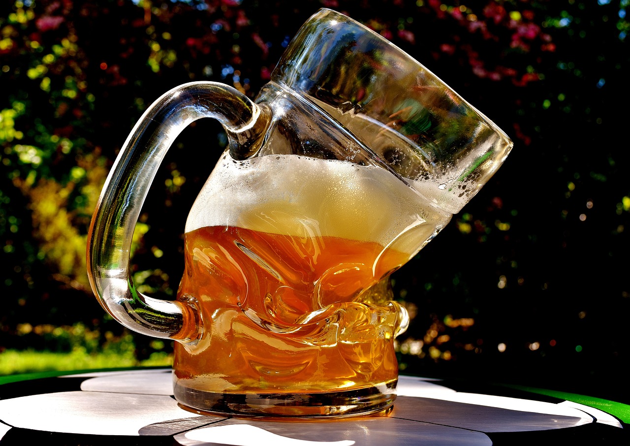 Oryginalny kufel o lekko wygiętym kształcie, wypełniony do połowy piwem.